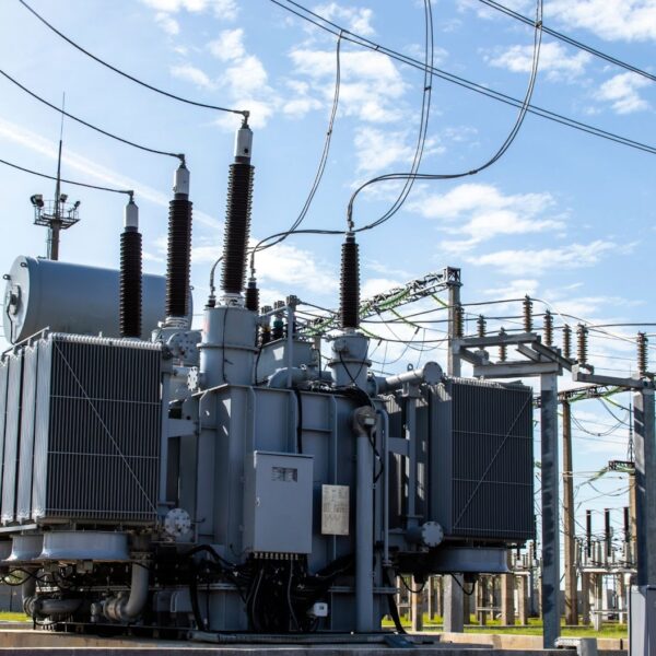 A-large-transformer-positioned-in-front-of-a-power-station-highlighting-industrial-safety-and-maintenance-practices A large transformer positioned in front of a power station highlighting industrial safety and maintenance practices